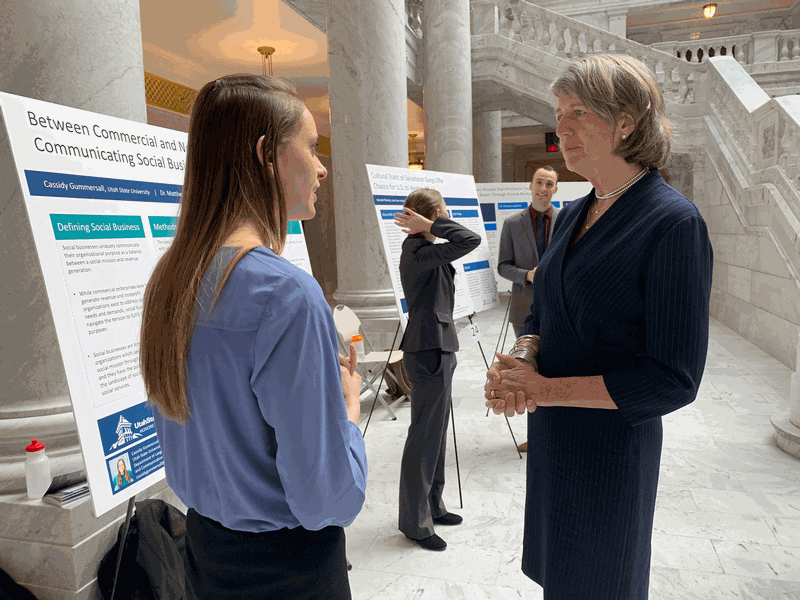 President Cockett listening as a USU student explains her research at the Utah State Capitol.