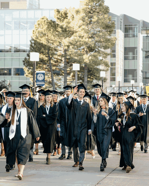 USU graduates walking towards the Spectrum from the Quad during the 2019 commencement exercises.