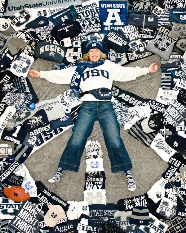 A future USU student lies on the ground, surrounded by dozens of USU-themed products and apparel.