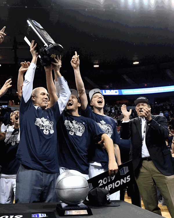 Coach Craig Smith of the USU Men's Basketball Team holding the Mountain West Conference trophy.
