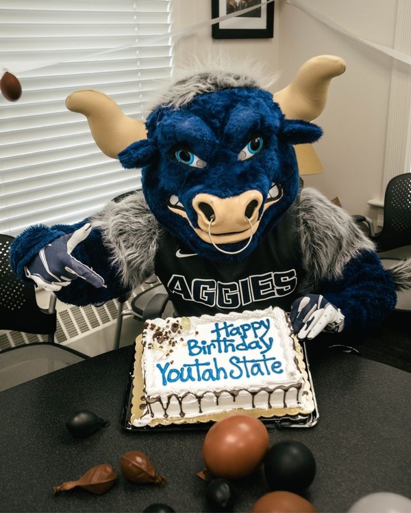 Big Blue poses with a misspelled cake in a conference room