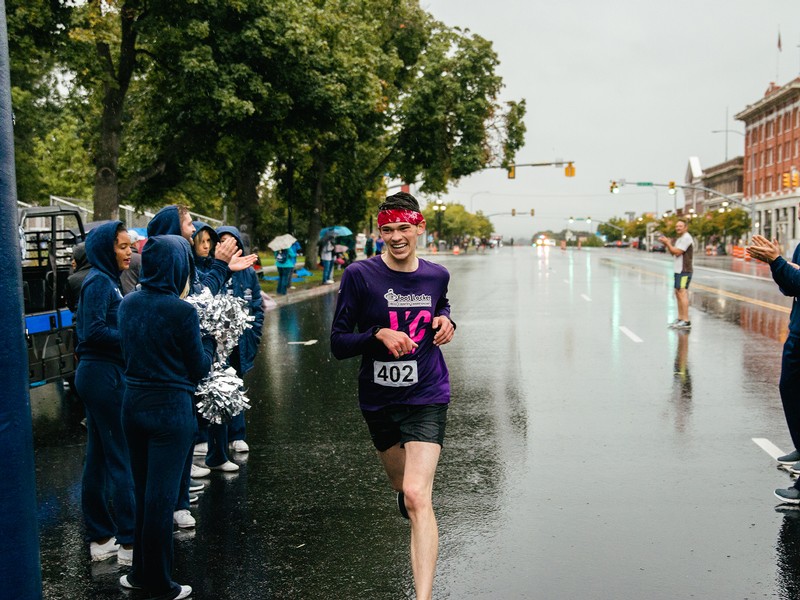 Runners cross finish line at the Homecoming 5k in the rain