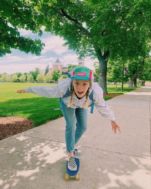 A female USU student skateboards on the sidewalk of the Logan campus quad.