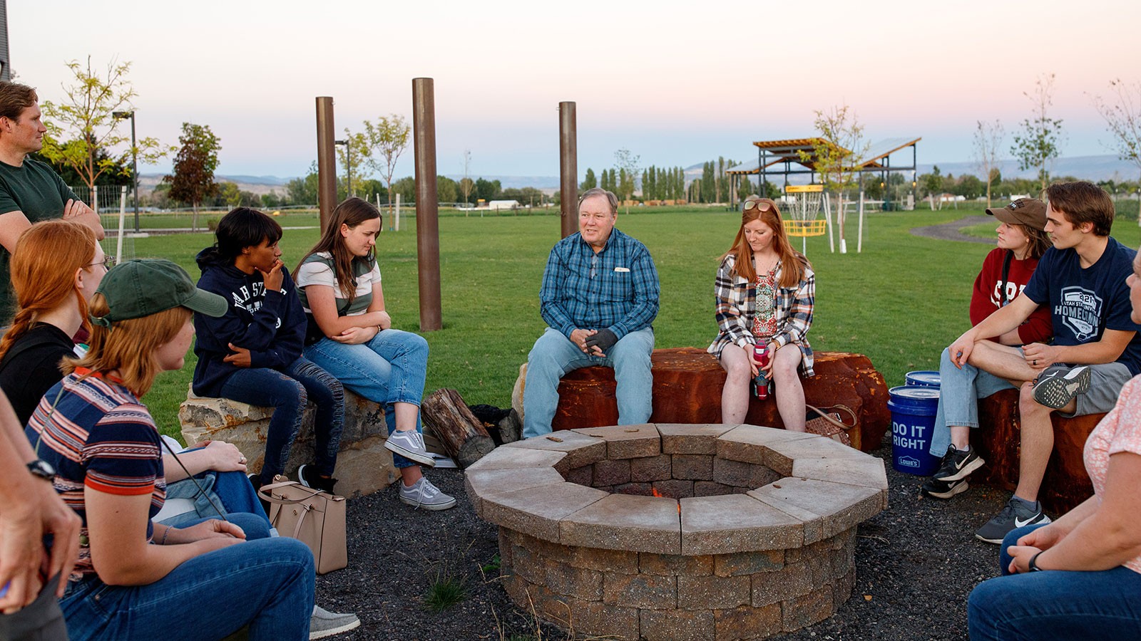 People at a fire pit in a park.